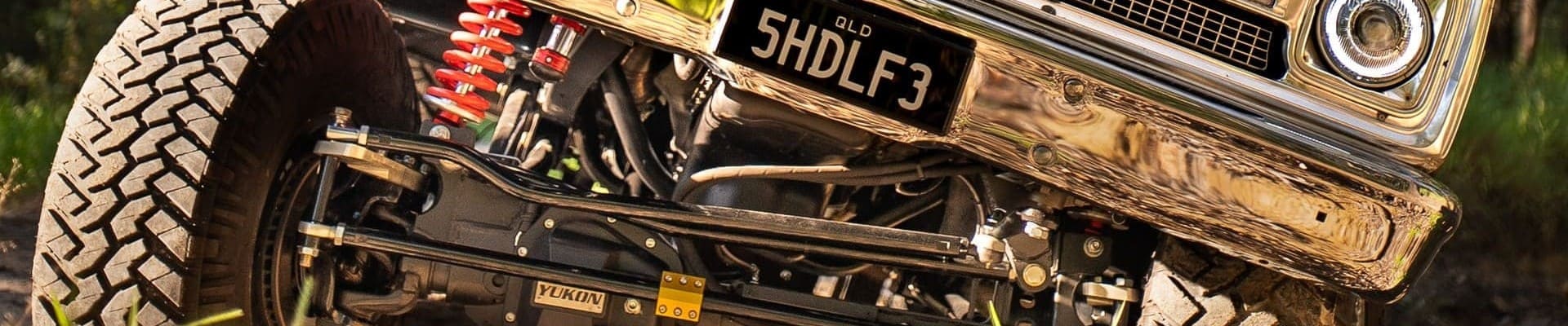 Chevrolet C20 vintage pickup truck with lifted suspension climbing over rough off-road terrain.